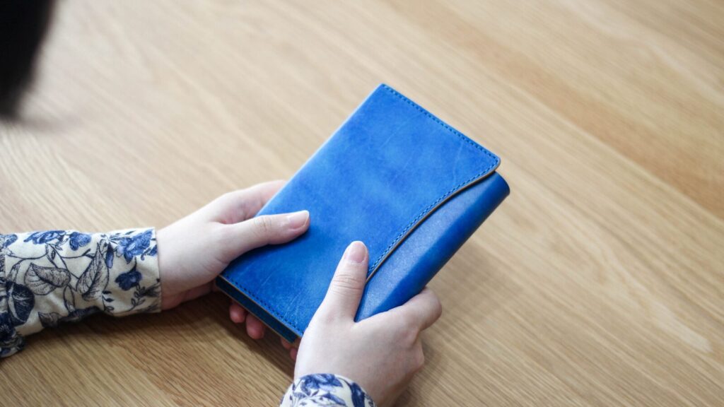 ブックカバー「OLIVE」ブルーを持っている様子。手染めの一点モノの美しさが際立つ