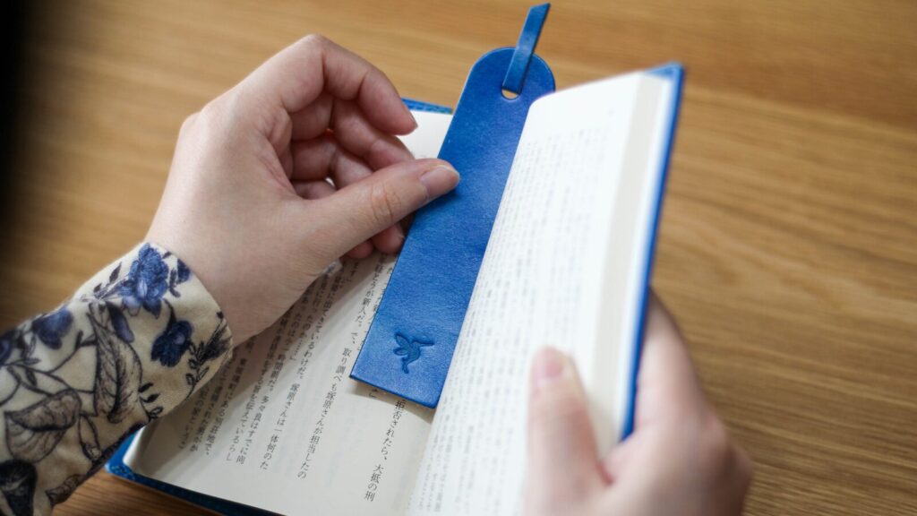 ブックカバー「OLIVE」の栞を挟む様子。栞も本革で本体と同じく手染め仕上げ。