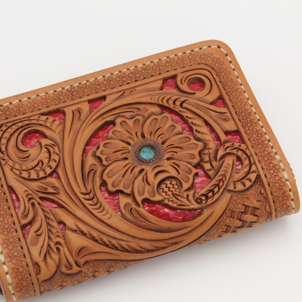 職人が手彫りで1つ1つの模様を表現。背景を切り取って蛇革を敷くことで奥行きのあるデザインに。