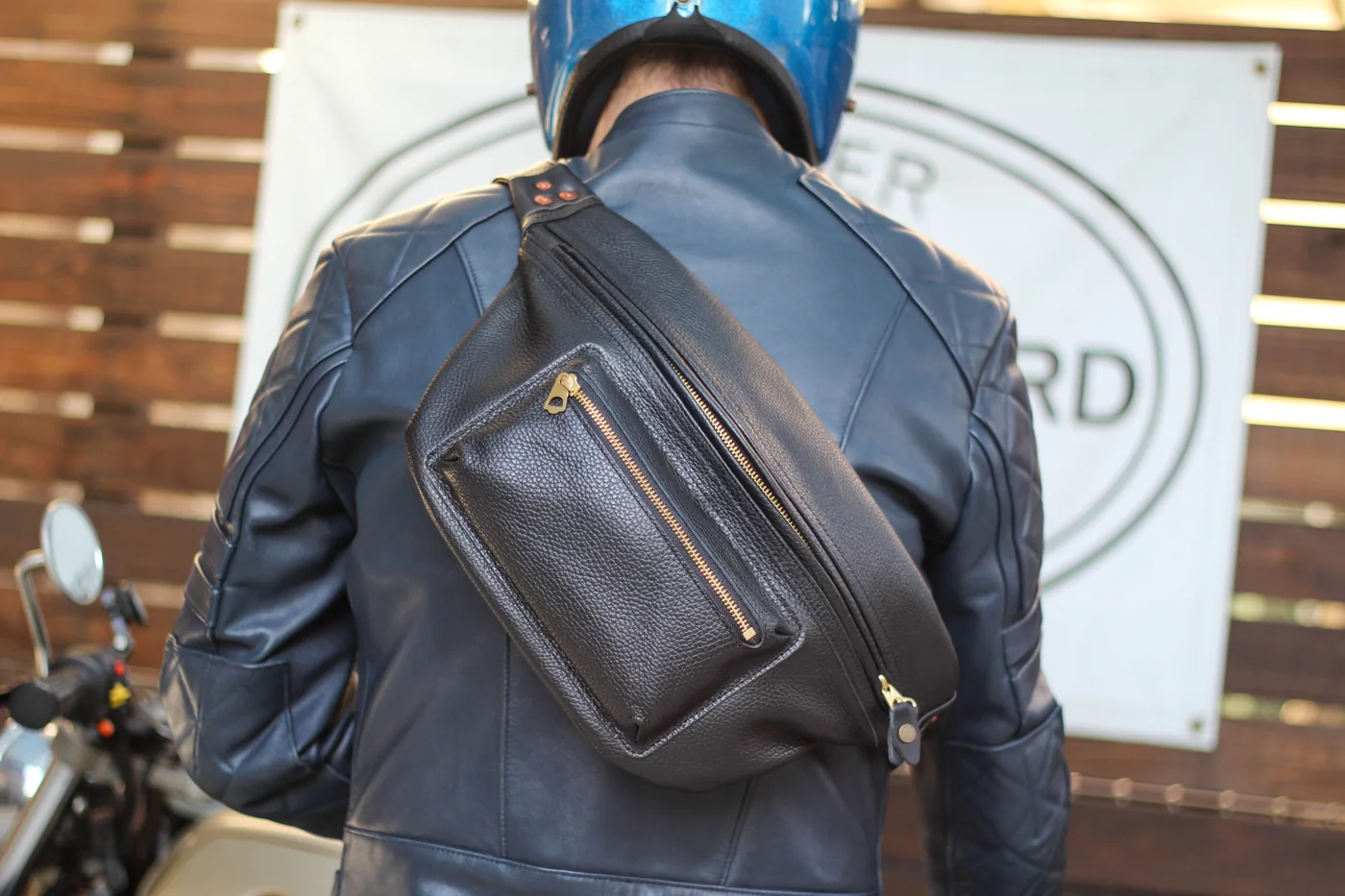 革のジャケットの背中にブラックのWanderを掛けた装い